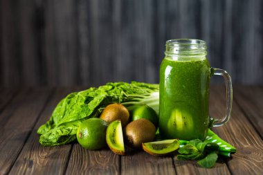 Ahşap masa seçici odak üzerinde malzemelerle karışık yeşil smoothie