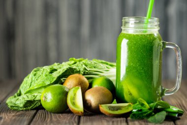 Ahşap masa seçici odak üzerinde malzemelerle karışık yeşil smoothie