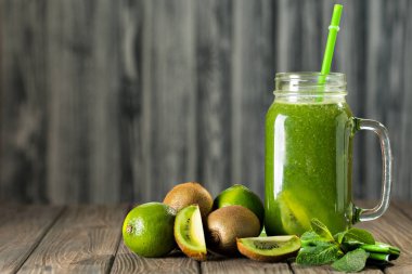 Ahşap masa seçici odak üzerinde malzemelerle karışık yeşil smoothie
