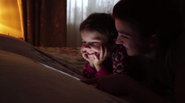 Anne ve küçük kızı evde tablet izlerken yakın çekim.