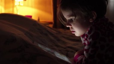 Tablet izlerken tam karanlıkta küçük şirin kız closeup