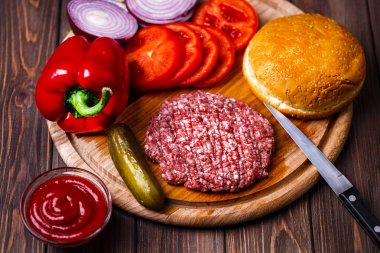 Ham zemin sığır eti Burger biftek pirzola baharat, peynir, domates, salata ve vintage ahşap kurullarında topuz
