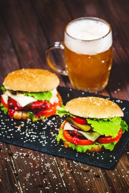 Bir bıçak ile ağız sulandıran, lezzetli ev yapımı hamburger closeup taş tahtaya sıkışmış. Koyu ahşap arka plan