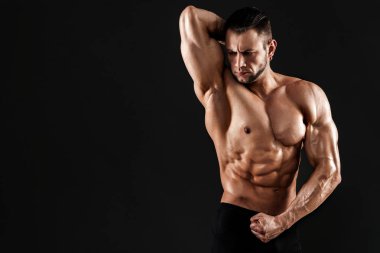 Stüdyoda siyah arka planda poz veren yakışıklı erkek model..