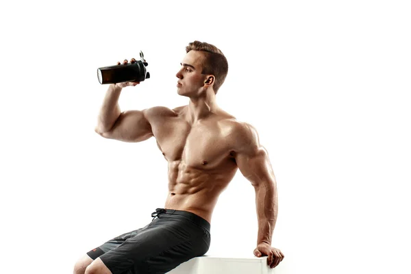 Hombre musculoso con bebida proteica en coctelera sobre fondo blanco — Foto de Stock
