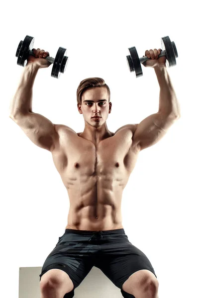 Hombre deportivo en el entrenamiento bombeando los músculos de la espalda y las manos con pesas . — Foto de Stock