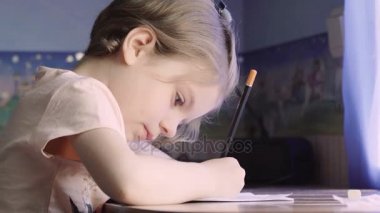 Küçük kız yazı ve çizim yapıyor. Ev ödevi yapıyordum. Yavrum. Sevimli kız..