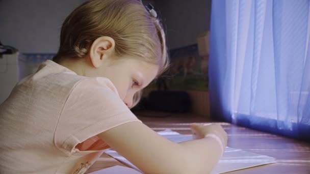 Красивая маленькая девочка пользуется ластиком дома — стоковое видео