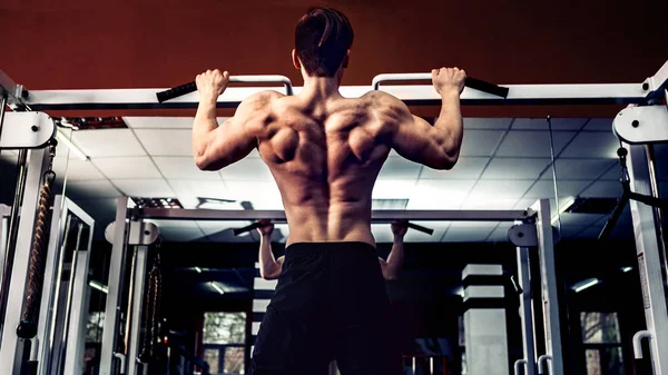 Young athlete exercising on bars in gym — Stock Photo, Image
