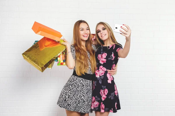 Mooie tiener meisjes uitvoering boodschappentassen en selfie overname met witte achtergrond — Stockfoto