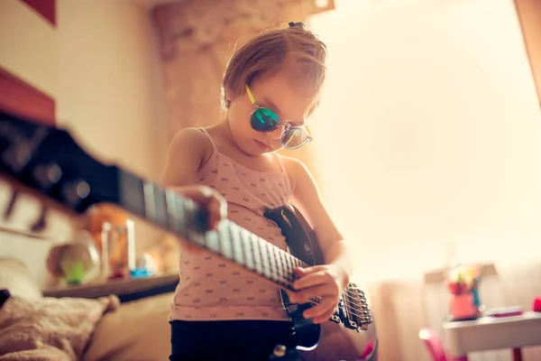 Söta lilla barn flicka i solglasögon som spelar gitarr. — Stockfoto