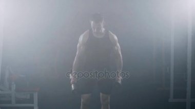 Güçlü genç kas erkek vücut geliştirmeci egzersiz pazı dumbbells vasıl jimnastik salonu ile.