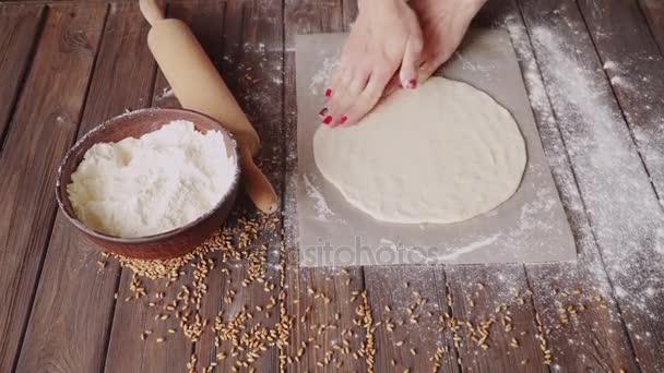 Жінка виливає тісто на обробну дошку на дерев'яний стіл, повний борошна на кухні вдома . — стокове відео