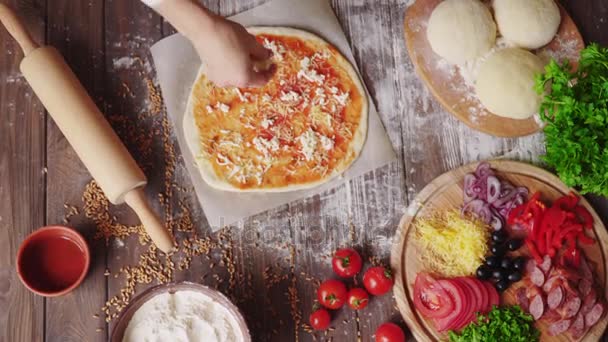 Frau legt Käse auf den Teig, während sie in der Küche Pizza backt — Stockvideo