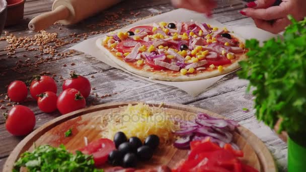Жінка кладе інгредієнти на тісто під час приготування піци на кухні — стокове відео