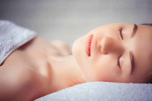 Health, beauty, resort and relaxation concept - beautiful woman in spa salon lying on the massage desk — Stock Photo, Image