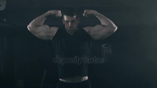 Bodybuilder flexing his muscles in gym. Smoke on background. — Stock Video