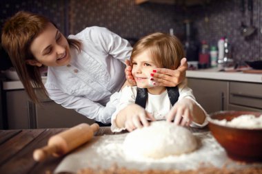 Kadın yemek pişiriyor ve küçük kızla eğleniyor.