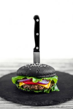 Close up of Homemade Black Burger with Cheese. Cheeseburger with black bun on white wooden background. clipart