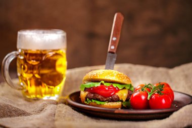 Ev yapımı sığır eti burger ve Kil çanak üzerinde taze sebze bardak bira rustik ahşap tablo, kopya alanı ile