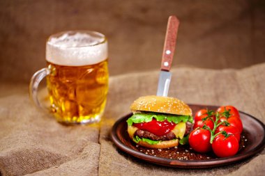 Ev yapımı sığır eti burger ve Kil çanak üzerinde taze sebze bardak bira rustik ahşap tablo, kopya alanı ile