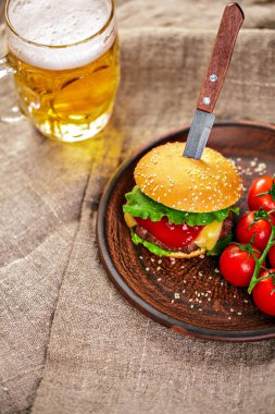 Ev yapımı sığır eti burger ve Kil çanak üzerinde taze sebze bardak bira rustik ahşap tablo, kopya alanı ile