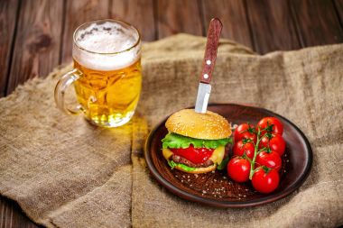 Ev yapımı sığır eti burger ve Kil çanak üzerinde taze sebze bardak bira rustik ahşap tablo, kopya alanı ile