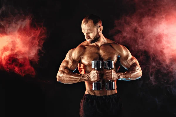 Fuerte deportista levantando pesada mancuerna en el humo —  Fotos de Stock