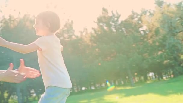 娘は母親の腕に突入し、彼女の大きな抱擁を与えます。公園の外. — ストック動画