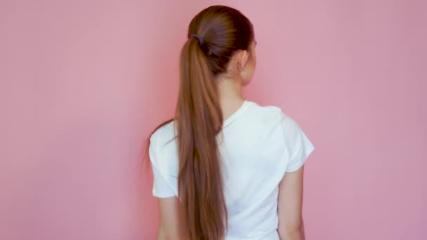 Mujer joven y bonita en diferentes movimientos. Capturado en Studio con fondo rosa. Regresa. — Vídeo de stock