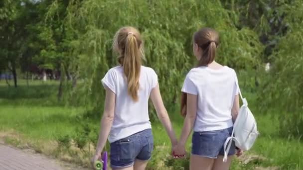 Ελκυστικά κορίτσια περπατώντας μέσα από το πάρκο και το χαμόγελο. φίλες που περνούν χρόνο μαζί υπαίθρια. αργή κίνηση — Αρχείο Βίντεο