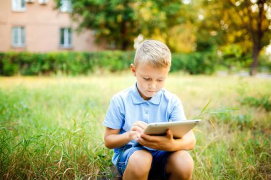 Genç çocuk daşu avlu ve tablet üzerinde bir oyun oynuyor