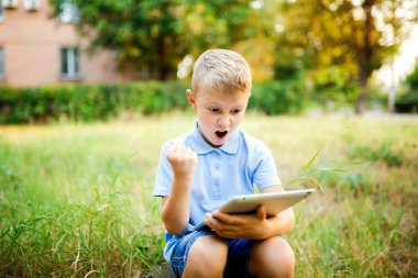 Genç çocuk daşu avlu ve tablet üzerinde bir oyun oynuyor