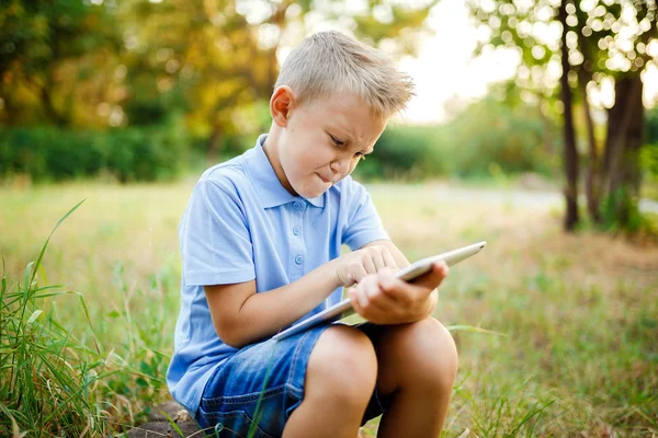 若い子供 sittingin 中庭とタブレットでゲームをプレイ — ストック写真