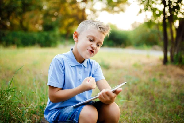 若い子供 sittingin 中庭とタブレットでゲームをプレイ — ストック写真