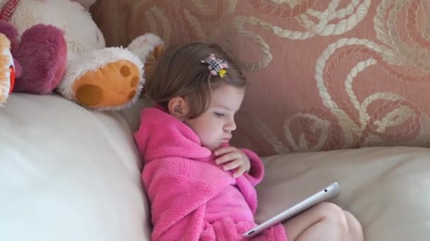 Маленькая милая девочка смотрит планшет — стоковое видео