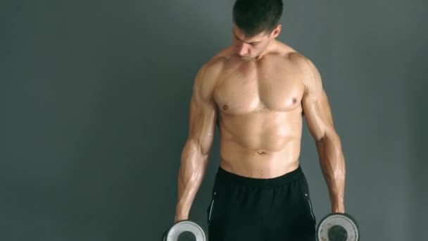 Koncentrerad topless bodybuilder utför biceps övning med hantlar. — Stockvideo