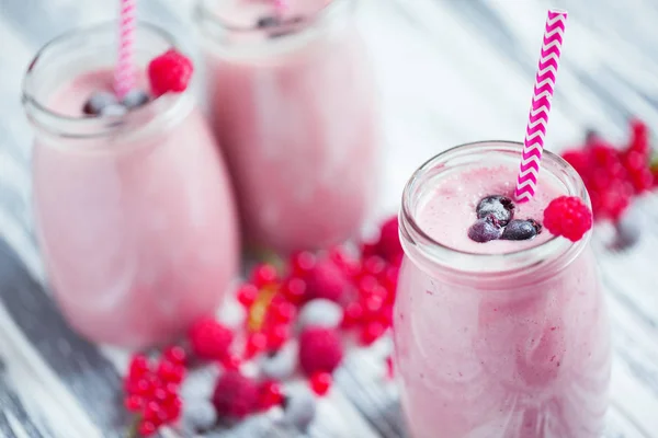 Milkshakes with berries in glass jars — Stock Photo, Image