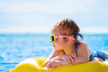 küçük kızı şişme beach şilte üzerinde yüzmek.