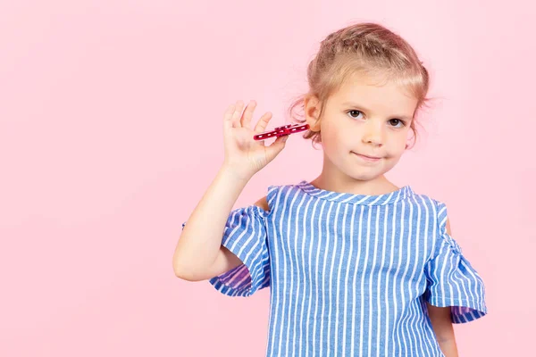 Girl in blue stripped shirt is playing red spinner in hand — Stock Photo, Image