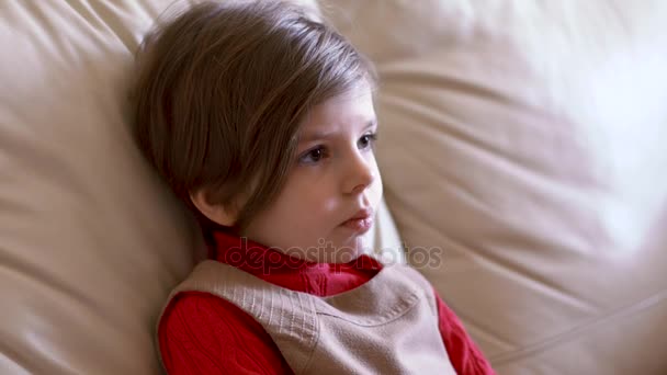 Linda niña sentada en el sofá y viendo la televisión — Vídeos de Stock