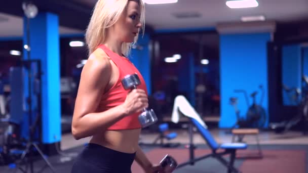 Видео спортивной женщины держат гантели и упорно тренируются в тренажерном зале — стоковое видео