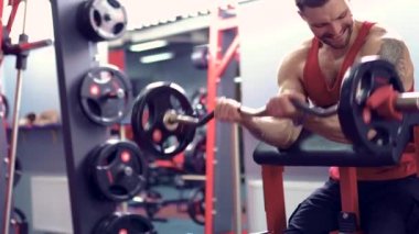 Adam vücut geliştirmeci bir spor salonunda bir halter egzersiz kümesi yapıyor. Gerçek zamanlı vurdu