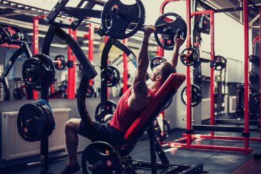 Simülatörde omuzlar için bir egzersiz yapan erkek