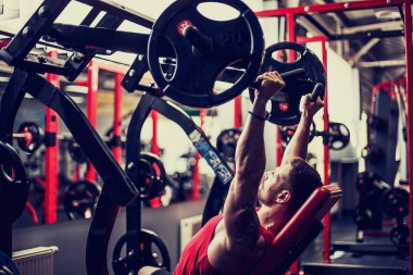 Simülatörde omuzlar için bir egzersiz yapan erkek