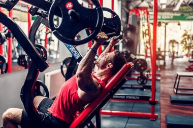 Simülatörde omuzlar için bir egzersiz yapan erkek