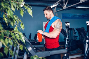 Adam bir havlu ve bir koşu bandı yanında shaker