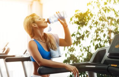 Güzel atletik sarışın kadın içme suyu spor salonunda bir koşu bandı üzerinde olduğunu.