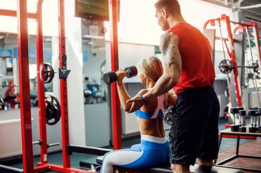 Sportif kız Yardımı salonunda kişisel onu antrenman ör ile ağırlık egzersizleri yapıyor.
