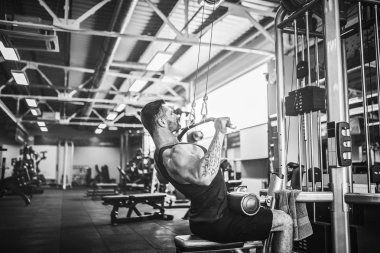 Arka üstünde makine için ağır egzersiz yaparak güçlü vücut geliştirmeci